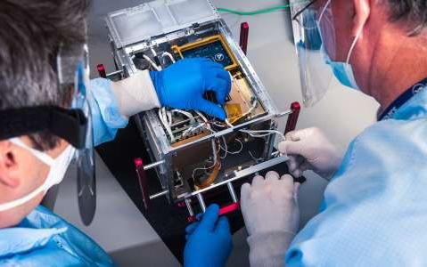 Image of scientists working on satellite payload